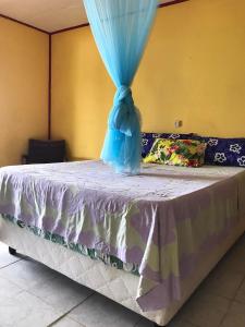 una cama con una cortina azul encima en Fare OKAI, en Fitii