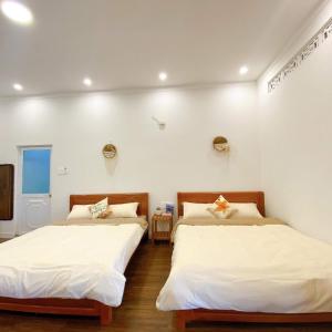 2 Betten in einem Zimmer mit weißen Wänden in der Unterkunft May Garden Pleiku Homestay in Plei Hơlăng