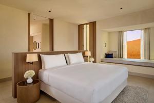 - une chambre avec un grand lit blanc et une fenêtre dans l'établissement The Ritz-Carlton Ras Al Khaimah, Al Wadi Desert, à Ras al Khaimah