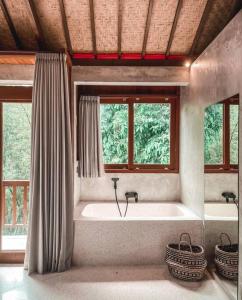 baño con bañera grande y 2 ventanas en Bukit Hideaway, en Uluwatu