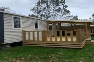 a mobile home with a porch and a deck at Camping Riva Bella in Ouistreham