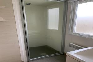 a glass shower in a bathroom with a window at Camping Riva Bella in Ouistreham