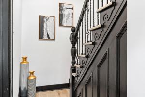 a hallway with a black and white staircase with pictures on the wall at Cozy 3BR Home close to Downtown Pittsburgh, minutes to attractions in Pittsburgh