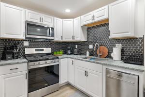 a kitchen with white cabinets and stainless steel appliances at Cozy 3BR Home close to Downtown Pittsburgh, minutes to attractions in Pittsburgh