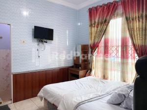 ein Schlafzimmer mit einem Bett und einem TV an der Wand in der Unterkunft Arjuna 1 Homestay Syariah Dieng RedPartner in Diyeng