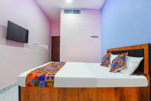 1 dormitorio con 1 cama y TV en la pared en FabExpress Evaan Deluxe Rooms, en Nagpur