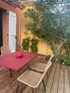 une table et des chaises rouges sur une terrasse en bois dans l'établissement Petite maison cocooning à Bormes les mimosas, à Bormes-les-Mimosas