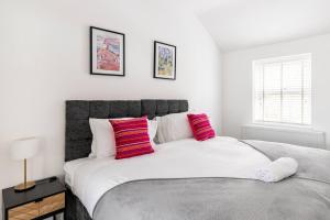 een slaapkamer met een groot wit bed met 2 rode kussens bij Impressive 4 Bed House Sleeps 8 Private Parking, Fast WiFi 2x Smart TVs Netflix & Foosball, Business Travellers Relocaters Leisure Welcome in Haversham