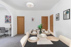 a dining room with a table with plates and chairs at Impressive 4 Bed House Sleeps 8 Private Parking, Fast WiFi 2x Smart TVs Netflix & Foosball, Business Travellers Relocaters Leisure Welcome in Haversham