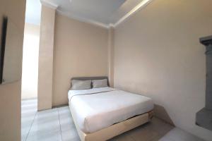 Un pequeño dormitorio con una cama blanca en una habitación en R Residence, en Medan