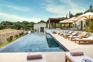 an infinity pool with lounge chairs and umbrellas at a villa at Eliamos Villas Hotel & Spa in Spartia