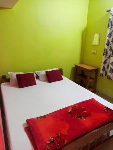 a bedroom with a white bed with a red blanket at Coorg Mists in Madikeri