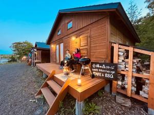 dos personas sentadas en la cubierta de una casita en Shirakaba no mori Cottage - Vacation STAY 55195v, en Abashiri