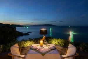 a dinner table with a view of the ocean at night at Cape Fahn Hotel - Private Islands Samui in Choeng Mon Beach