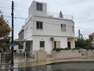 ein weißes Gebäude an der Straßenseite in der Unterkunft BLUE LUXURY APARTMENT (BREAKBOOKING CY-SERVICES LTD) in Limassol