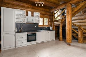 uma cozinha com electrodomésticos brancos e tectos em madeira em Loghouse Madeira, Fužine. em Fužine
