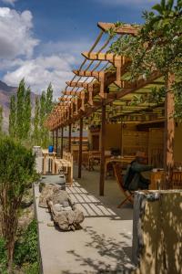 a wooden pavilion with tables and chairs in a field at Nubra Ecolodge in Liekzan