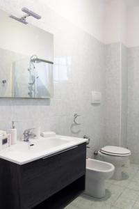 a white bathroom with a sink and a toilet at Stanze di Sofia in Bari