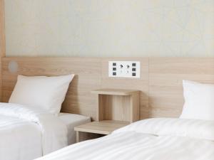 duas camas com lençóis brancos e uma mesa de cabeceira entre eles em Tabino Hotel EXpress Narita em Narita