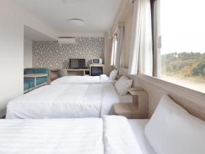 um quarto de hotel com três camas e uma janela em Tabino Hotel EXpress Narita em Narita