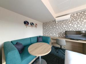 sala de estar con sofá azul y mesa en Tabino Hotel EXpress Narita en Narita