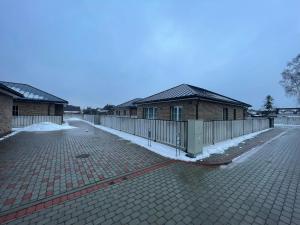 a building with a fence and snow on the ground at MA apartments in Mažeikiai