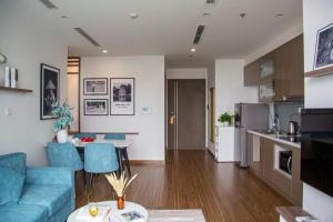 Il comprend un salon avec un canapé bleu et une cuisine. dans l'établissement Vinhomes Westpoint Apartment - by Bay Luxury, à Hanoï