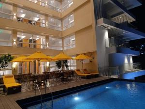 a hotel with a pool and tables and yellow umbrellas at Regenta Place Vasco Goa in Vasco Da Gama