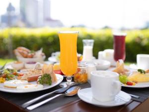 a table with plates of food and glasses of orange juice at Ibis Bangkok Riverside in Bangkok