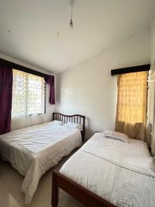 Mopearlz 4bedroom villa Nyali في مومباسا: سريرين يجلسون بجانب بعض في غرفة النوم