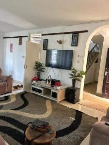 Mopearlz 4bedroom villa Nyali في مومباسا: غرفة معيشة مع تلفزيون بشاشة مسطحة وأريكة