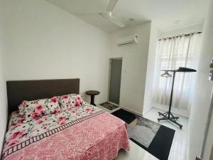 a bedroom with a bed with a pink blanket at RB HOMESTAY in Merlimau