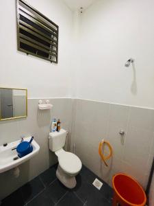 y baño con aseo blanco y lavamanos. en RB HOMESTAY en Merlimau