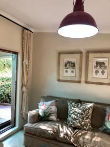 a living room with a couch and a large light fixture at Houghton Rosebank Cottage with deck overlooking pool in Johannesburg