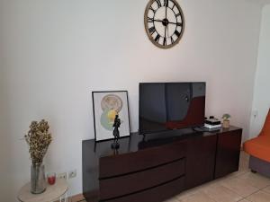 - un salon avec une télévision et une horloge murale dans l'établissement Appartement meublé, à La Possession