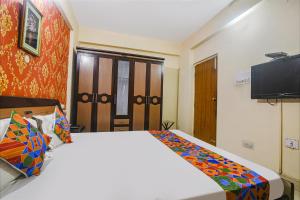una camera con un grande letto e una televisione di FabHotel Maadhavam Residence a Patna