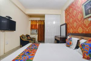 um quarto de hotel com uma cama e uma televisão em FabHotel Maadhavam Residence em Patna