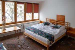 a bedroom with a bed and a table and windows at Podkroví v Kabinetu CB in České Budějovice