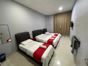 fila de camas en una habitación de hotel en SZA INN HOTEL, en Kampong Kerayong
