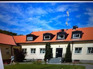 Un uomo che passa davanti a una casa con un tetto arancione di Ekängens Pensionat Garde a Ljugarn
