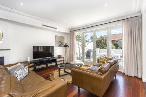 a living room with a couch and a television at Cottesloe Aqua Retreat - Executive Escapes in Perth