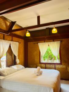 duas camas num quarto com duas janelas em พลารมย์ รีสอร์ต แอนด์ โฮมสเตย์ em Ban Chang