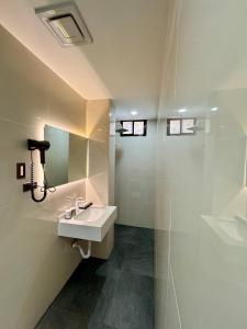 uma casa de banho branca com um lavatório e um chuveiro em LuckyTito Dmall Boracay em Boracay