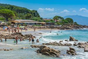 un groupe de personnes sur une plage dans l'eau dans l'établissement Grand studio route des sanguinaires vue mer panoramique, à Ajaccio