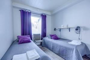 two beds in a room with purple curtains at Lomahuoneisto Skivillas 28 A 10 in Hyrynsalmi +26 photos