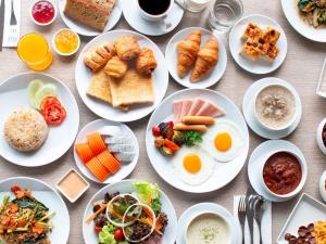 a table with plates of breakfast food on it at ibis Styles Bangkok Sukhumvit 4 in Bangkok
