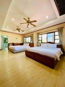1 dormitorio con 2 camas y ventilador de techo en พลารมย์ รีสอร์ต แอนด์ โฮมสเตย์, en Ban Chang