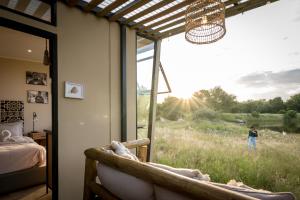 een slaapkamer met een raam met uitzicht op een veld bij Kamoka Camp in Hoedspruit