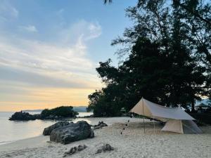 Cosy HomeStay at Penang Island -Beach and Village في بايان ليباس: خيمة بيضاء على شاطئ رملي بالقرب من الماء