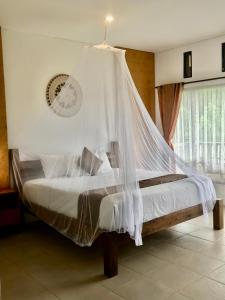 - une chambre avec un lit et une moustiquaire dans l'établissement Kraras Munduk Guest House & DonBiyu Rendezvous Restaurant, à Munduk